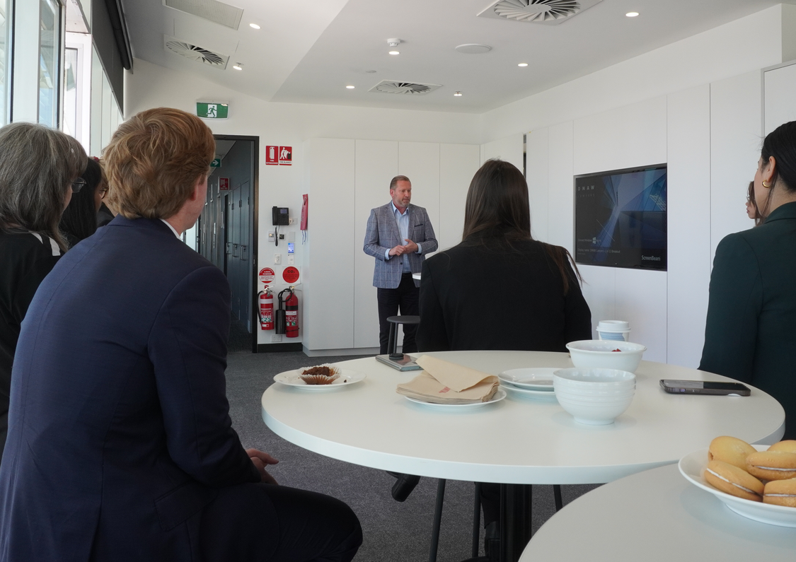 A room of professionals enjoying morning tea while listening to a speaker