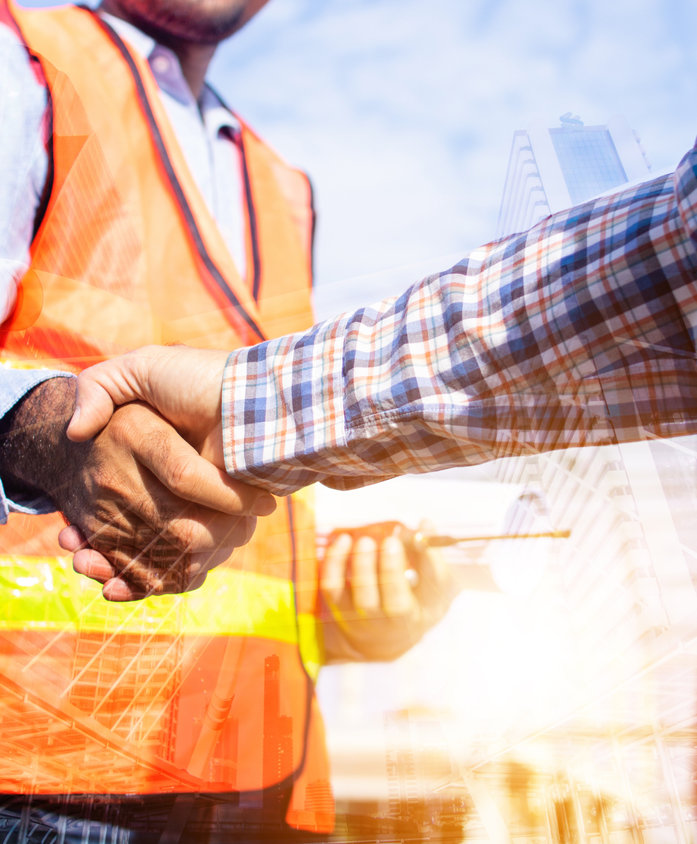 A contractor wearing hi-vis shaking hands with another person wearing a checkered shirt