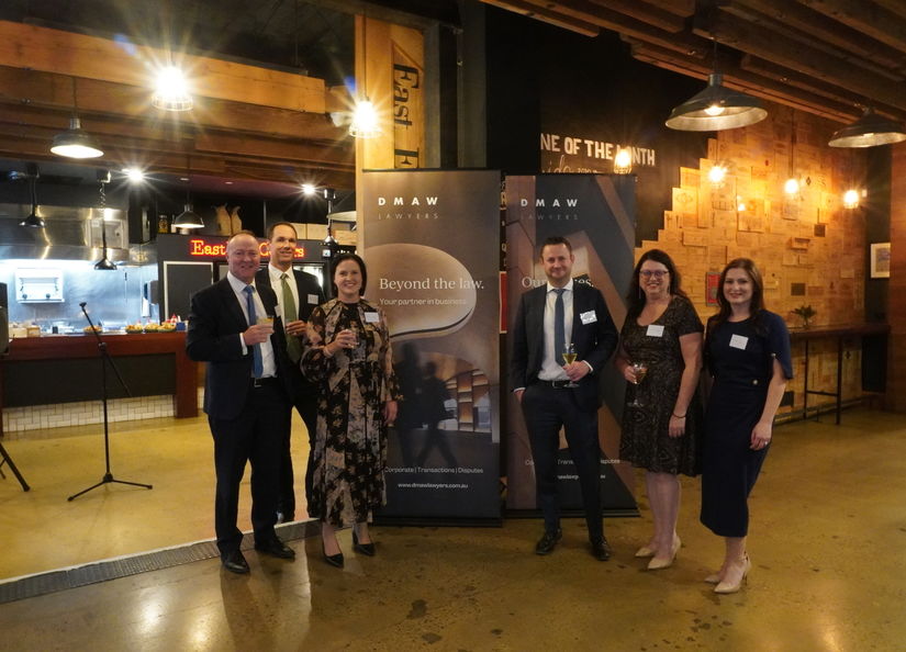 A group of nicely dressed professionals standing in East End Cellars in front of company banners