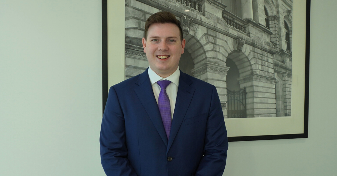 Young lawyer standing in front of a print looking proud.