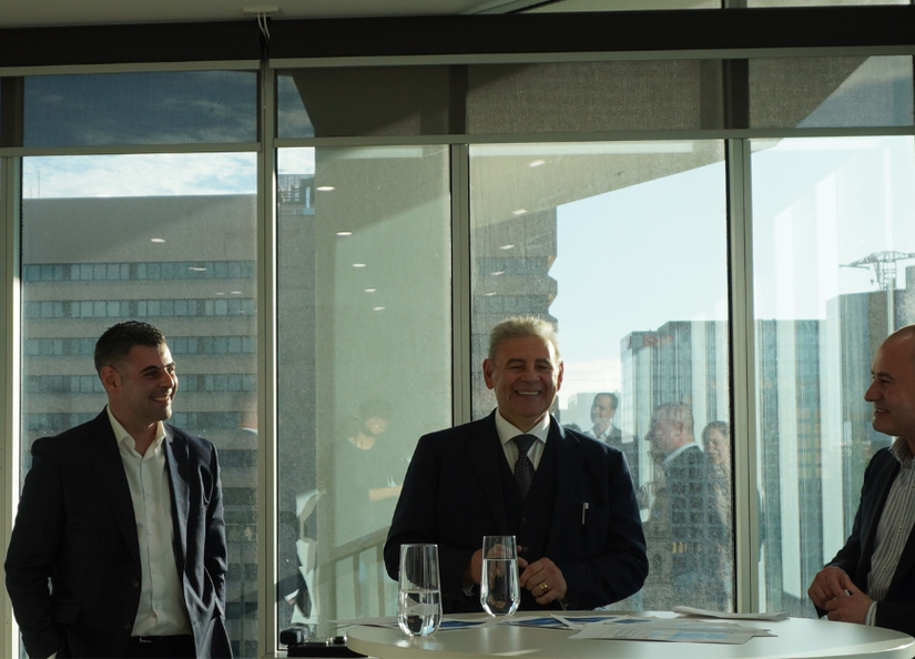 Three professional men looking happy, giving a presentation to a group with the Adelaide city scape in the background