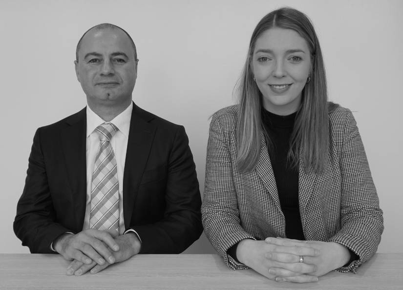 Man and woman sitting at desk with arms crossed