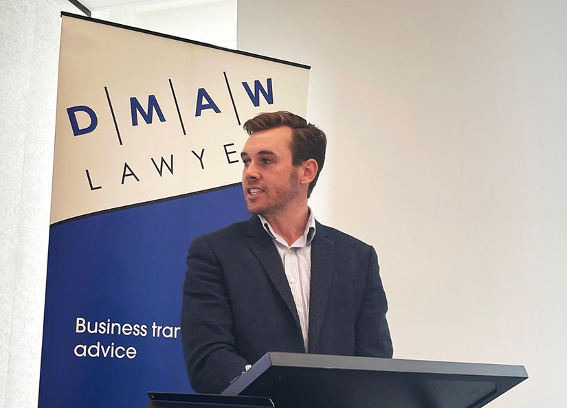 Man giving presentation with DMAW Lawyers' banner in background