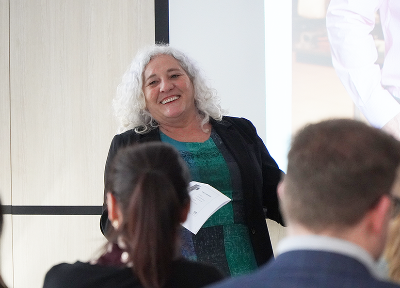 Happy woman with long grey hair presenting to a team of staff