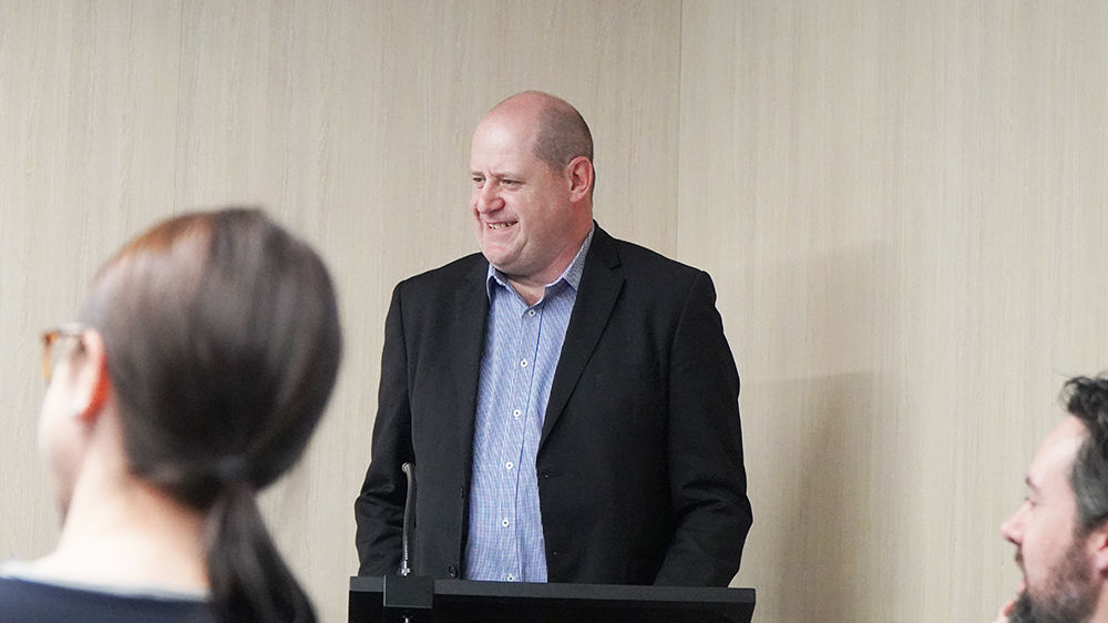 A professionally dressed man giving a presentation