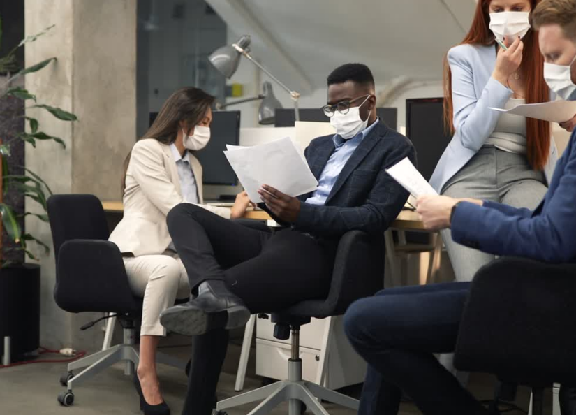 Group of young professionals working in an office wearing masks
