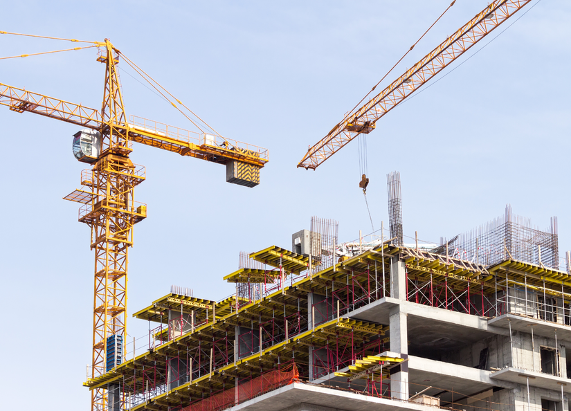 A construction work site with cranes and scaffolding in view.