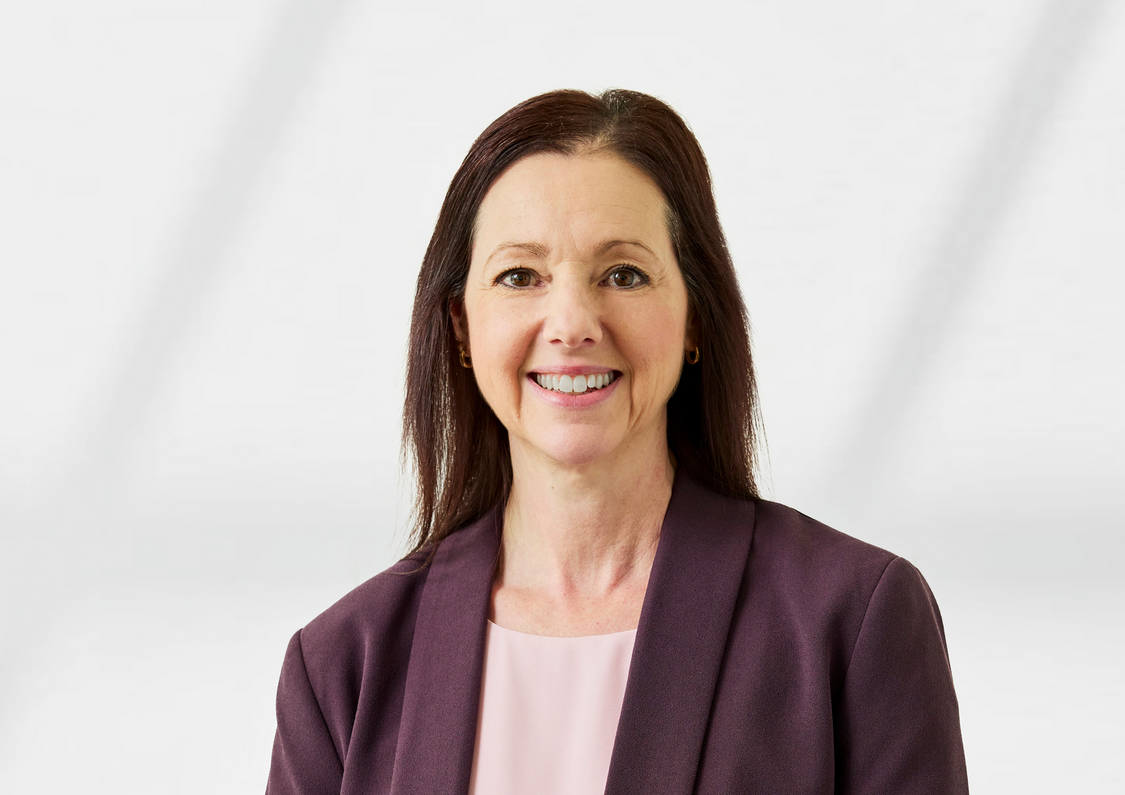 Pauline Niquet wearing an aubergine blazer and pink shirt. Her hair is brown.