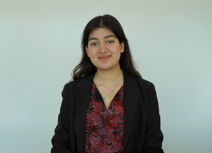 Young woman dressed professionally sitting in front of white wall