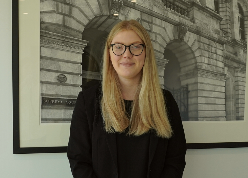 Young blonde professional looking woman standing in front of a print of court houses