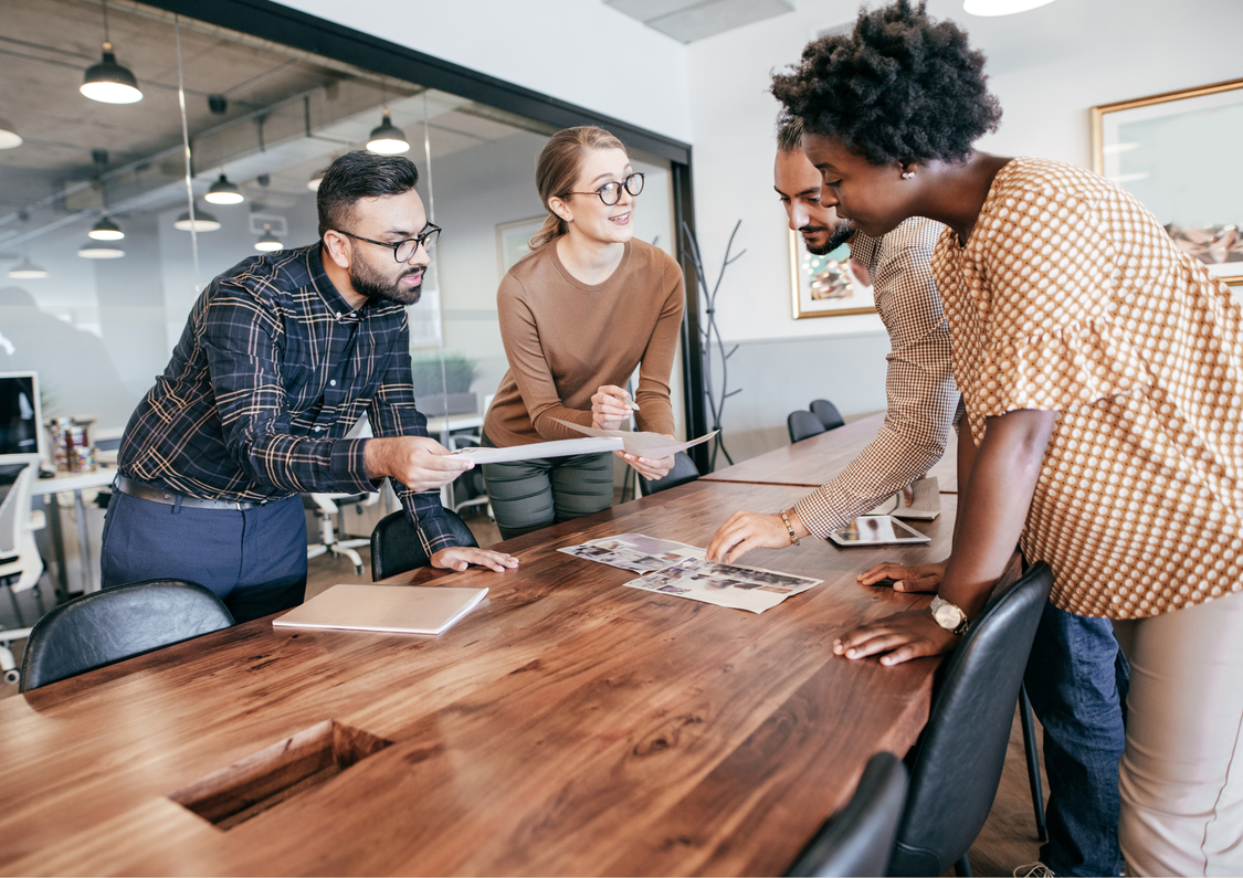 A group of staff leaning over a boardroom table discussing something