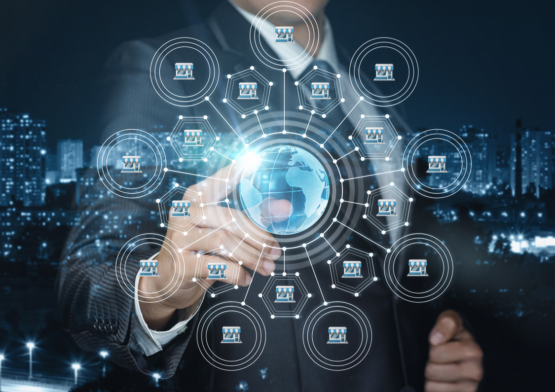 An image of a man in a suit touching a computer generated world with buildings around it